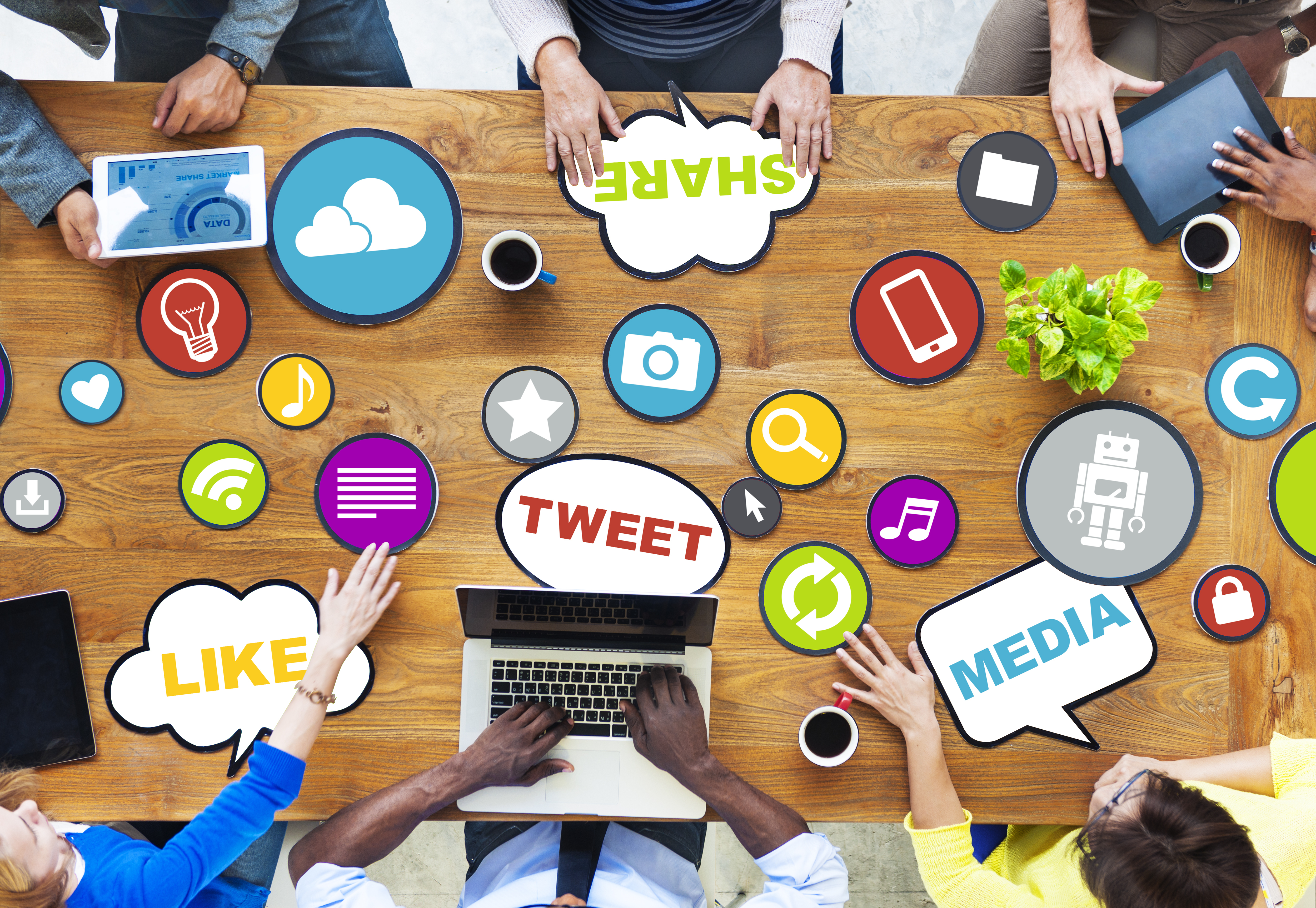 people sitting around conference table with social media icons on table